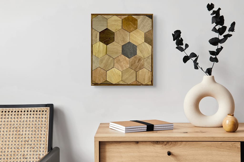 Hexagon wood wall art in warm neutral tones hanging above a light wood dresser with modern vases and books