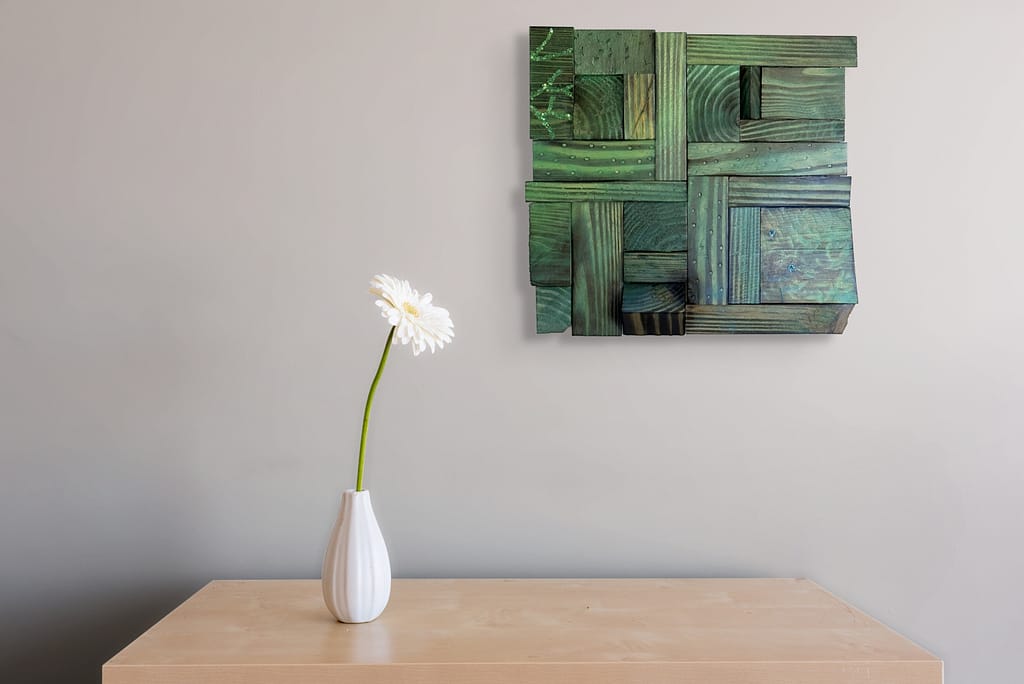 Finished Shou Sugi Ban geometric wood wall art with green and blue ombre, displayed above a table.