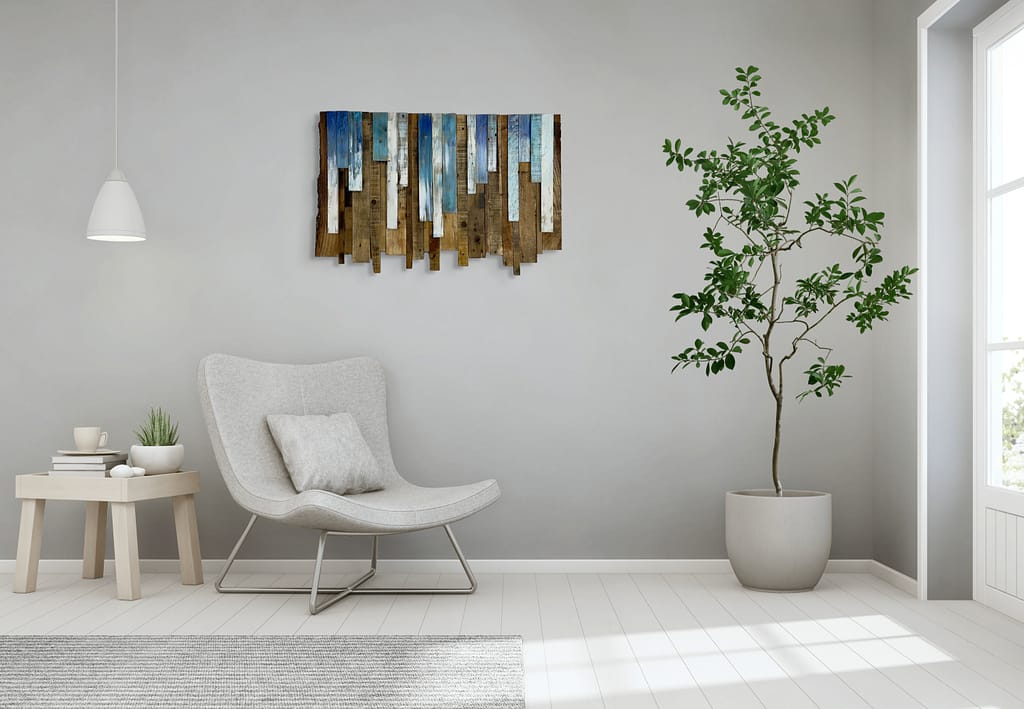 Reclaimed wood wall art with blue and white accents hanging above a modern white chair in a bright living room