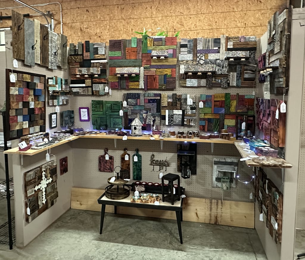 Detailed view of the glitter art and burned wood crafts at Mcatz Creations booth.