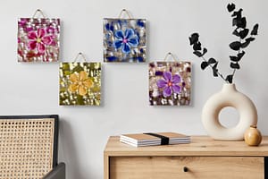 Four colorful metal flower wall art pieces mounted on wood, hanging together above a cabinet