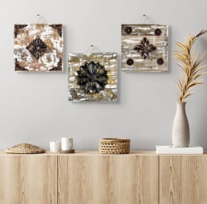 Three rustic reclaimed wood flower wall art pieces in different colors hanging together above a cabinet