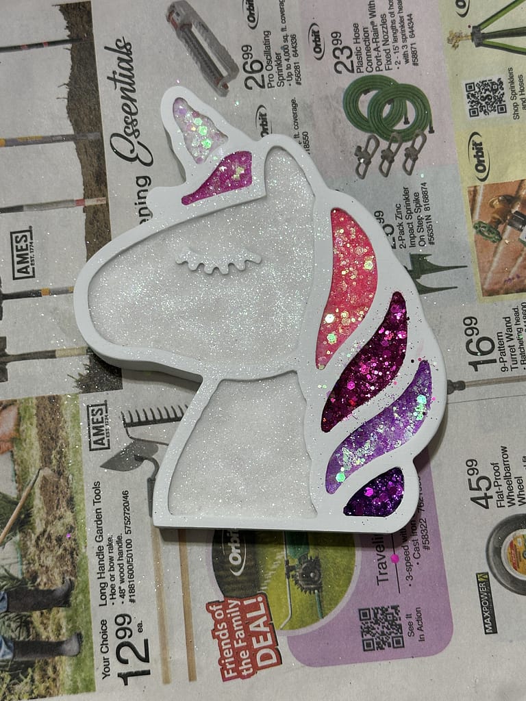 Close-up of handmade unicorn wall art with a glittery pink and purple mane, sealed in glossy epoxy.