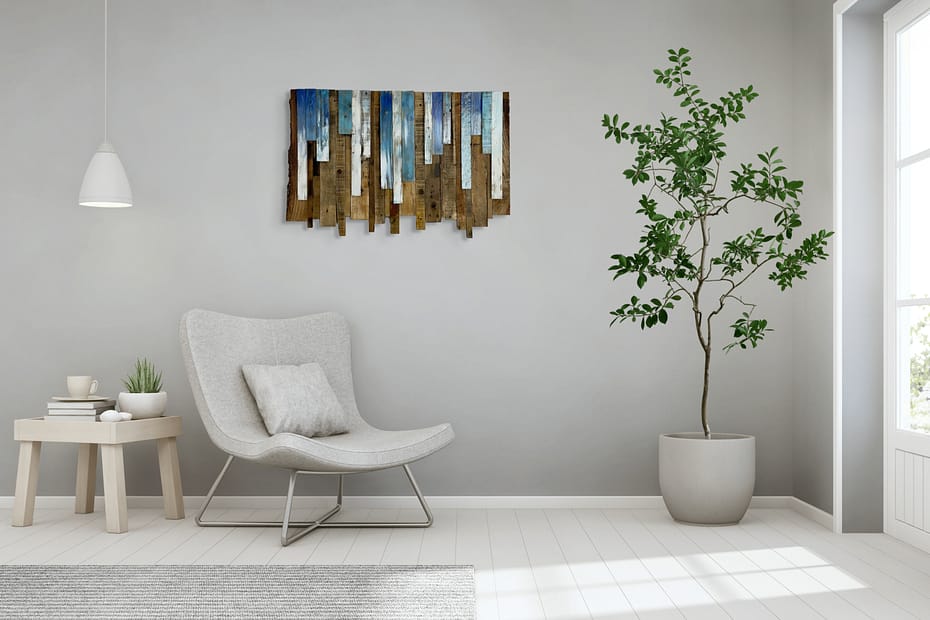 Reclaimed wood wall art with blue and white accents hanging above a modern white chair in a bright living room